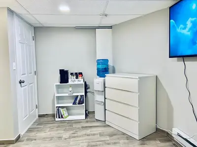 a room with a tv and a white wall at Bright, Stylish and Comfy Luxury Room With Workspace! in Haledon