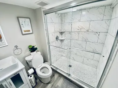 a bathroom with a shower and a toilet and a sink at Bright, Stylish and Comfy Luxury Room With Workspace! in Haledon
