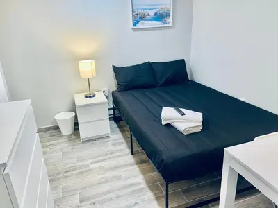a small bedroom with a bed with a blue bedspread at Bright, Stylish and Comfortable Room with Workspace! in Haledon