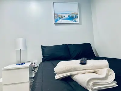 a bedroom with a bed with a remote control on it at Bright, Stylish and Comfortable Room with Workspace! in Haledon