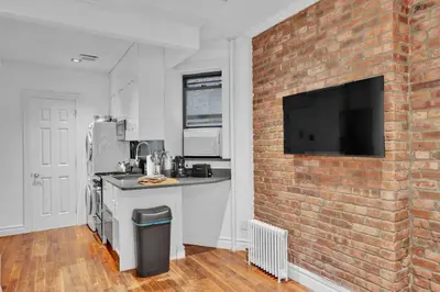a kitchen with a brick wall with a tv on it at Spacious SoHo 1Bedroom Unit Washer & Dryer in New York
