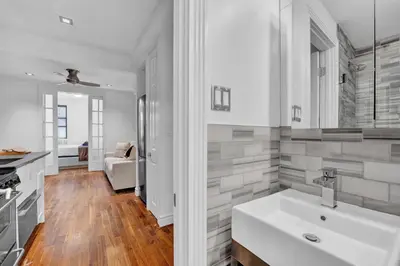 a white bathroom with a sink and a living room at Spacious SoHo 1Bedroom Unit Washer & Dryer in New York