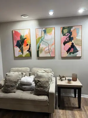 a living room with a couch and four paintings on the wall at Hot tub, Sauna, fire pit, games and nature in Lake Poconos in Pocono Summit
