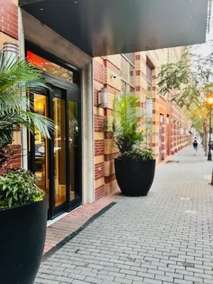 a brick building with two large potted plants on a sidewalk at Hudson River waterfront apt w sweeping NYC views in Hoboken