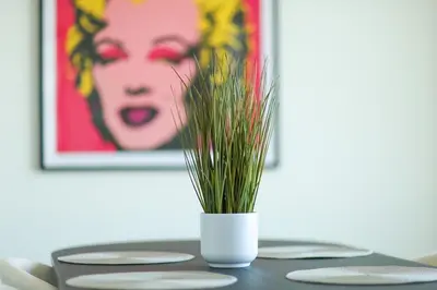 a white vase with grass in it on a table at Hudson River waterfront apt w sweeping NYC views in Hoboken