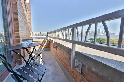 a balcony with a table and chairs and the ocean at Hudson River waterfront apt w sweeping NYC views in Hoboken