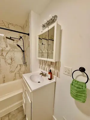 a white bathroom with a sink and a shower at Spacious 3BR Apartment - 12min Newark Airport -Near NYC & Malls in Newark