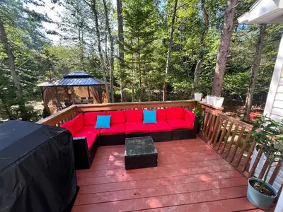 a red couch on a deck with a gazebo at Golden Deer Lodge in Tobyhanna