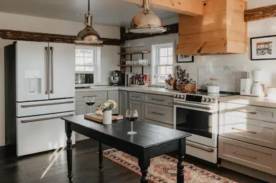 a kitchen with a table and two glasses of wine at Luxe Gabel Farmhouse Fire Pit & Country Views in Callicoon