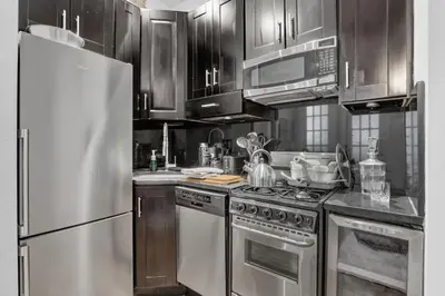 a kitchen with stainless steel appliances and wooden cabinets at Modern 2BR with Private Garden - In Gramercy Park in New York