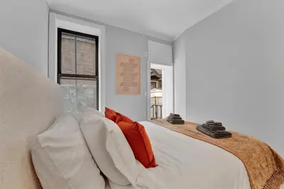 a bedroom with a large white bed with orange pillows at Modern 2BR with Private Garden - In Gramercy Park in New York