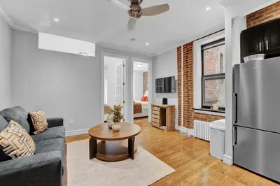 a living room with a couch and a refrigerator at Modern 2BR with Private Garden - In Gramercy Park in New York