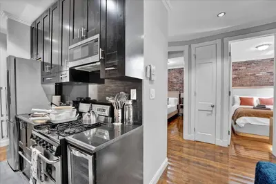a kitchen with stainless steel appliances and a bedroom at Gramercy Apartment - 3BR 2BA Modern Central in New York