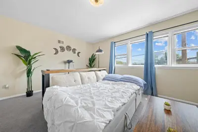 a bedroom with a large bed and windows at Spacious Apartment - 3 min Train to NYC in Bayonne