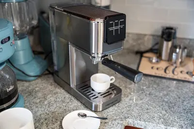 a coffee machine on a counter with a cup in it at Spacious Apartment - 3 min Train to NYC in Bayonne