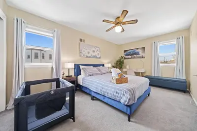 a bedroom with a blue bed and a ceiling fan at Spacious Apartment - 3 min Train to NYC in Bayonne