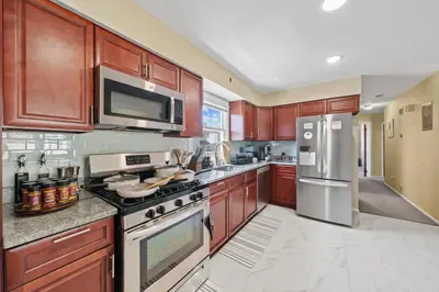 a kitchen with wooden cabinets and stainless steel appliances at Spacious Apartment - 3 min Train to NYC in Bayonne