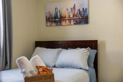 a bedroom with a bed with a painting on the wall at Spacious Apartment - 3 min Train to NYC in Bayonne