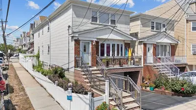 a house with a staircase in front of it at Spacious Apartment - 3 min Train to NYC in Bayonne