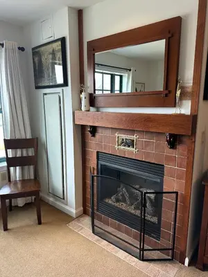 a fireplace with a mirror and a chair in a room at Cozy Studio Resort Stay Mountain Creek Pool Hiking in Vernon Township