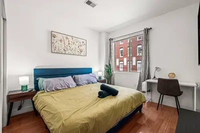 a bedroom with a bed and a desk and a window at New Modern Apt in Chinatown Parking Available in Philadelphia