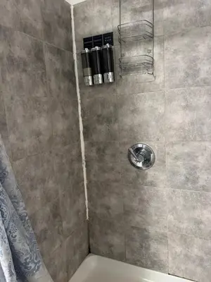 a shower with a gray tiled wall and a shower at Private Basement near NYC and NJ attractions in East Orange