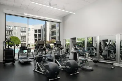 a gym with cardio equipment and a large window at AVE Clifton - Furnished Apartment, Clifton NJ in Clifton