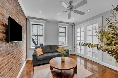 a living room with a couch and a brick wall at Elegant 3BR-2BA in Gramercy -Modern & Central in New York