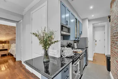 a kitchen with white cabinets and a vase of flowers on a counter at Elegant 3BR-2BA in Gramercy -Modern & Central in New York