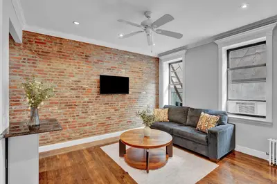 a living room with a couch and a brick wall at Elegant 3BR-2BA in Gramercy -Modern & Central in New York