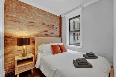 a bedroom with a brick wall and a bed at Elegant 3BR-2BA in Gramercy -Modern & Central in New York