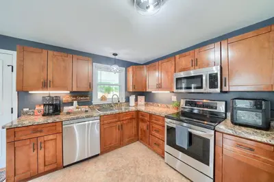 a kitchen with wooden cabinets and stainless steel appliances at Walnut Street Retreat with Hot Tub, 3 Bedrooms in Ephrata