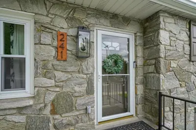 a stone facade of a house with two windows at Walnut Street Retreat with Hot Tub, 3 Bedrooms in Ephrata