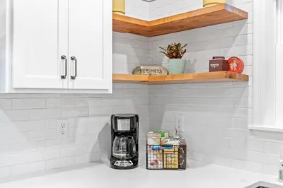 a kitchen with white cabinets and a coffee maker on a counter at The Respite getaway in Harrisburg