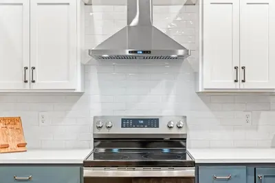a stove top oven in a kitchen with white cabinets at The Respite getaway in Harrisburg