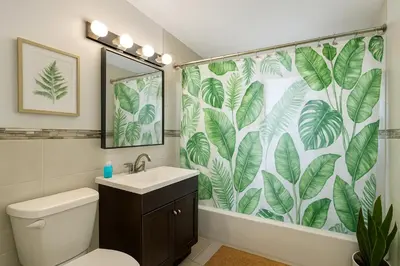a bathroom with a toilet and a shower curtain with leaves at 2 BR Apt|15 Min to NYC|Book Today in North Bergen