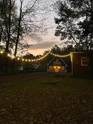 a string of lights on a house at night at Cozy Winter Chalet on 5 Acres - Fire Pit & Views in Livingston Manor