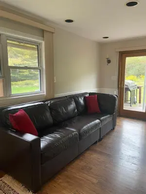 a black leather couch with red pillows in a living room at Cozy Winter Chalet on 5 Acres - Fire Pit & Views in Livingston Manor