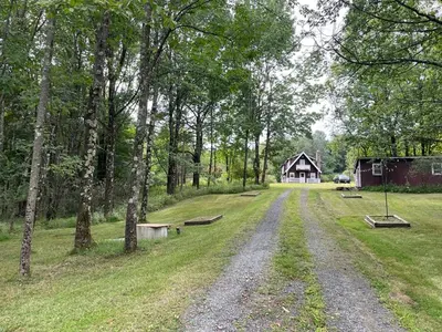 a dirt road with a house in the background at Cozy Winter Chalet on 5 Acres - Fire Pit & Views in Livingston Manor
