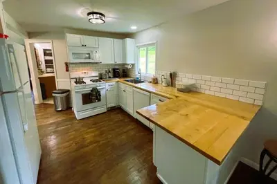 a kitchen with white cabinets and a wooden counter top at Cozy Winter Chalet on 5 Acres - Fire Pit & Views in Livingston Manor