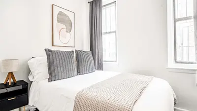 a white bedroom with a bed and two windows at 2 Bedroom Apartment in Midtown Manhattan - Near NYC Icons! in New York