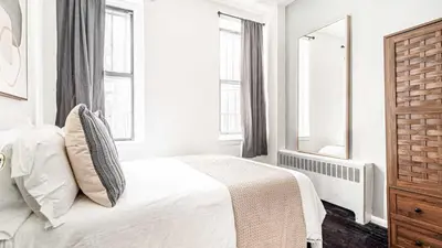 a white bedroom with a bed and two windows at 2 Bedroom Apartment in Midtown Manhattan - Near NYC Icons! in New York