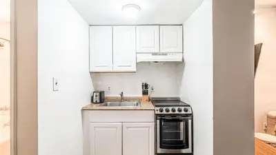 a small kitchen with white cabinets and a sink at 2 Bedroom Apartment in Midtown Manhattan - Near NYC Icons! in New York