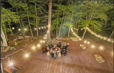 a group of people sitting at a table in the woods at night at The Woodland Escape in Lake Harmony