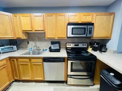 a kitchen with wooden cabinets and a stove and microwave at Pet-Friendly 1BR Condo Free Parking, Discount! in Elkins Park