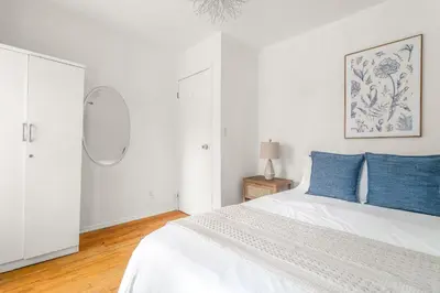 a white bedroom with a white bed with blue pillows at Spacious 3BR Apartment in Kips Bay - Central Manhattan Location! in New York