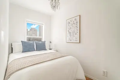 a white bedroom with a bed and a window at Spacious 3BR Apartment in Kips Bay - Central Manhattan Location! in New York
