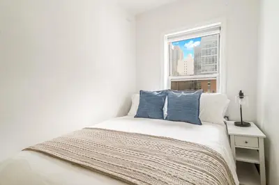 a white bedroom with a bed and a window at Spacious 3BR Apartment in Kips Bay - Central Manhattan Location! in New York
