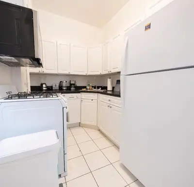 a kitchen with white cabinets and a white refrigerator at Spacious 3BR Near Columbia Uni & Riverside Park in New York