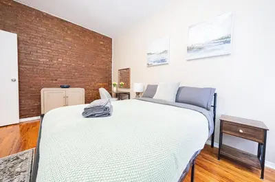 a bedroom with a large bed and a brick wall at Spacious 3BR Near Columbia Uni & Riverside Park in New York